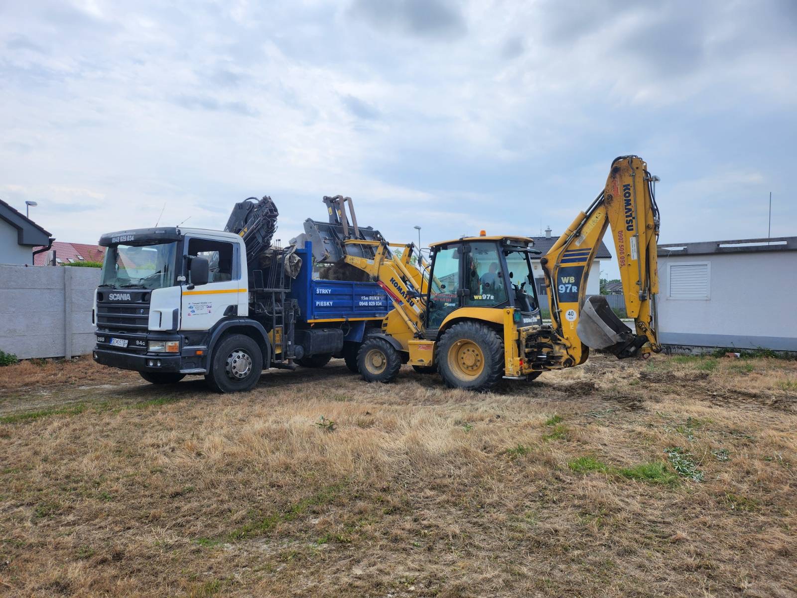 Truck and backhoe prepared for ground work on site.