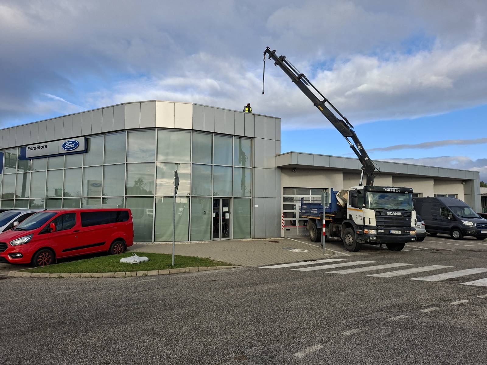 Hydraulic crane working beside a commercial building.